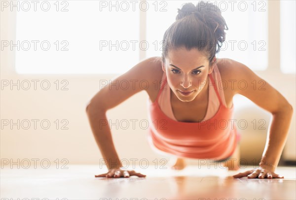 Close up of Hispanic woman doing push-ups in gym