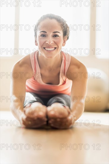 Close up of Hispanic woman stretching in gym