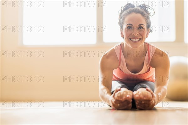 Close up of Hispanic woman stretching in gym