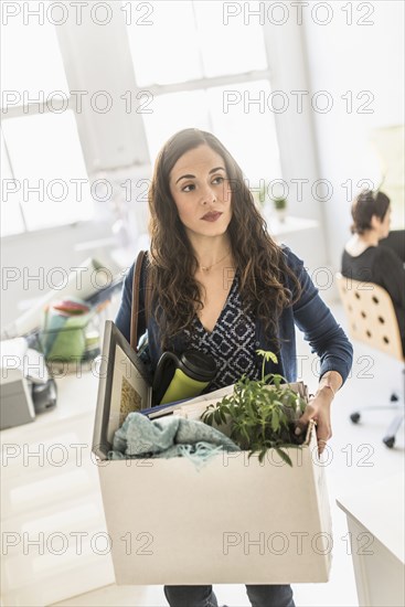 Businesswoman carrying cardboard box in office