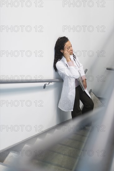 High angle view of stressed mixed race doctor standing on staircase