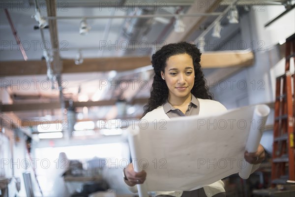 Mixed race architect reading blueprints