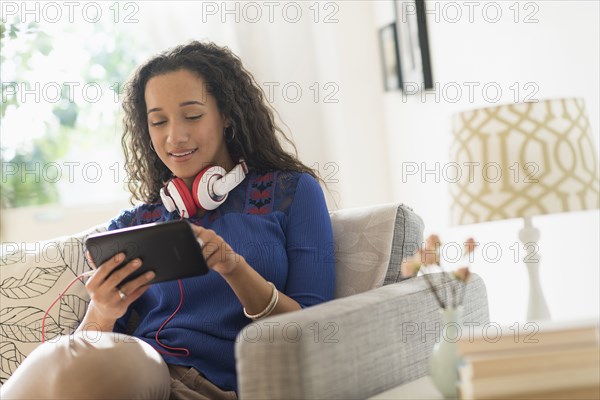 Mixed race woman using digital tablet on sofa