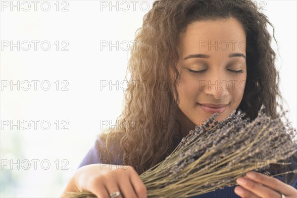 Close up of mixed race woman smelling dried lavender flowers