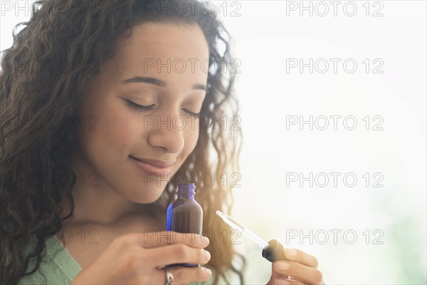 Close up of mixed race woman smelling aromatherapy oil