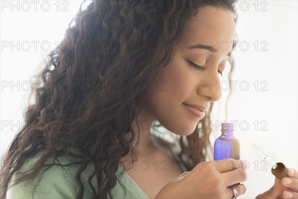 Close up of mixed race woman smelling aromatherapy oil