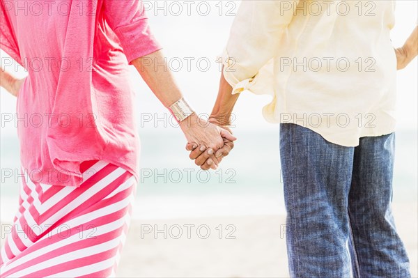 Older couple holding hands on beach