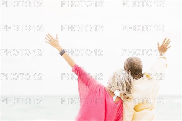 Older couple cheering and hugging on beach