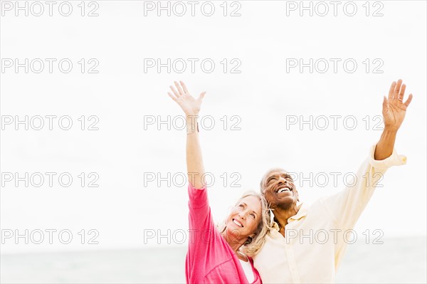Older couple cheering and hugging on beach