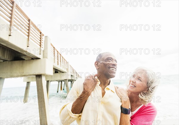 Older couple walking under boardwalk on beach