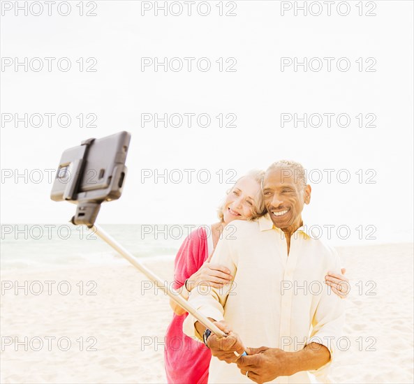 Older couple taking cell phone photograph on beach