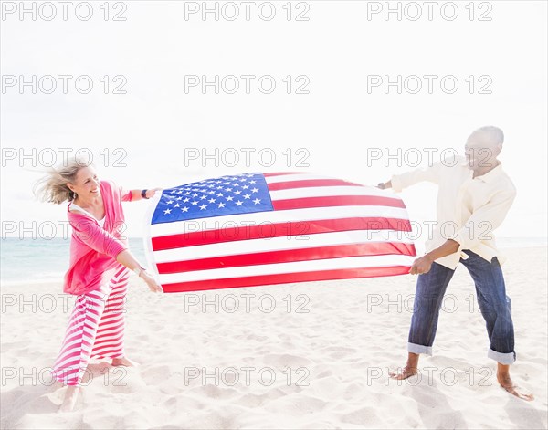 Older couple holding American flag on beach