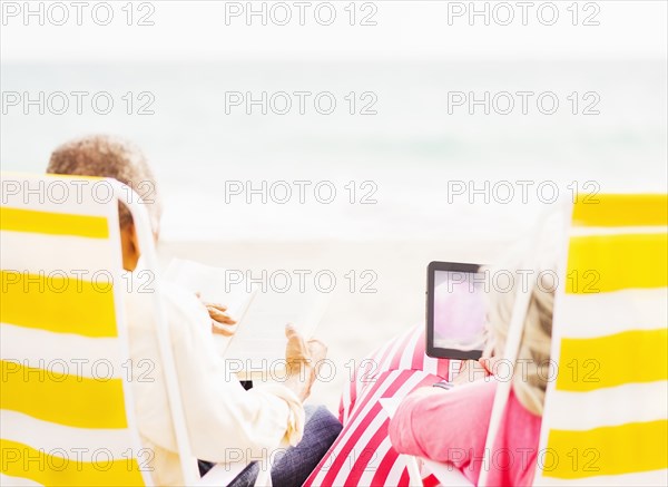 Older couple relaxing in lawn chairs on beach