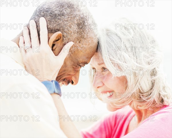 Older couple touching foreheads on beach