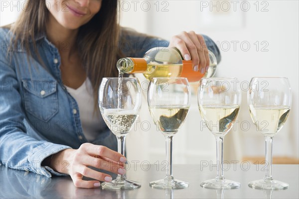 Caucasian woman pouring glasses of white wine