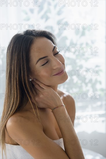 Caucasian woman rubbing her neck on massage table