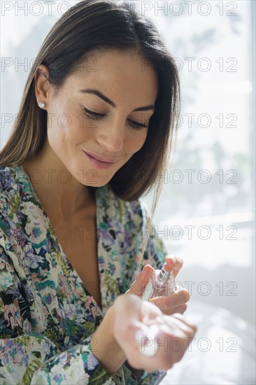 Caucasian woman spraying perfume on wrist