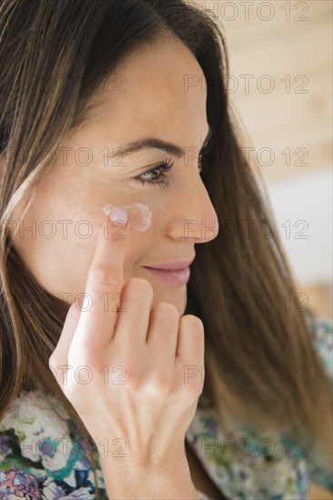 Caucasian woman applying moisturizer to face