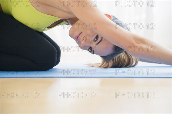 Caucasian woman stretching on yoga mat