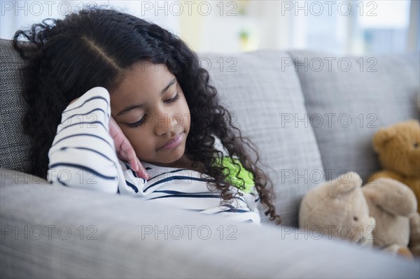 Sad mixed race girl sitting on sofa