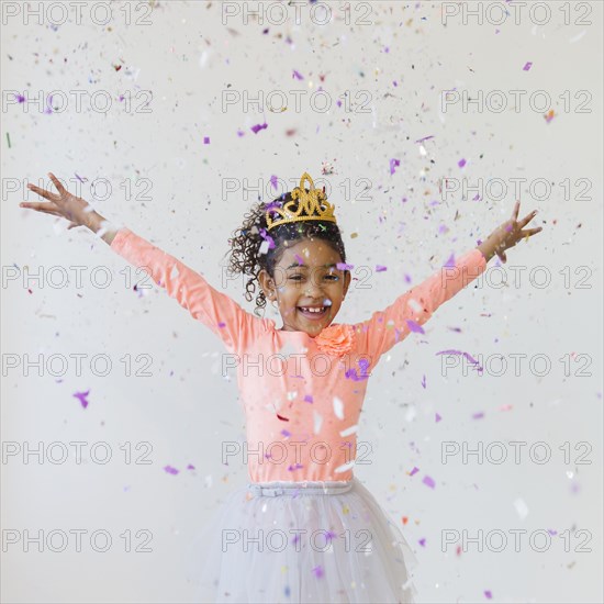 Mixed race girl wearing tiara throwing confetti