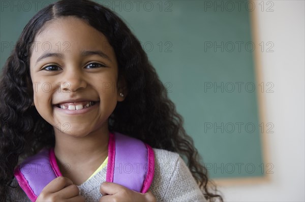 Smiling mixed race student wearing backpack in classroom