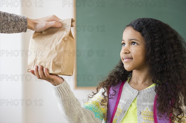 Student taking brown bag lunch in classroom