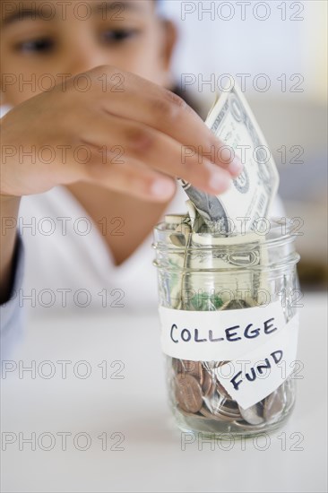 Mixed race girl saving money in college fund jar