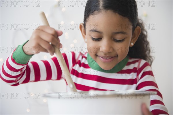 Close up of mixed race girl stirring dough