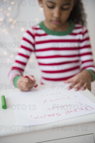 Mixed race girl writing letter to Santa