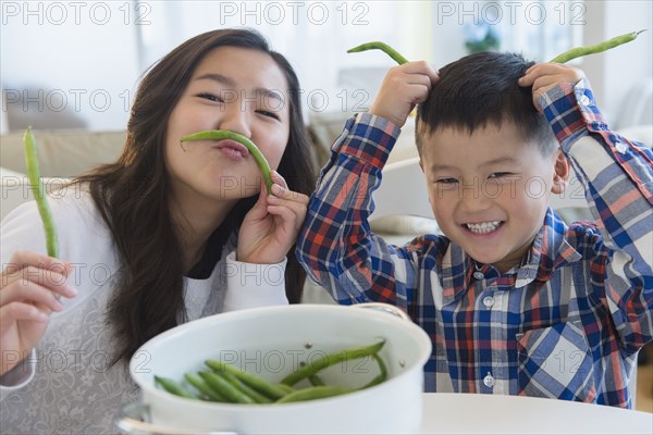 Asian brother and sister playing with vegetables