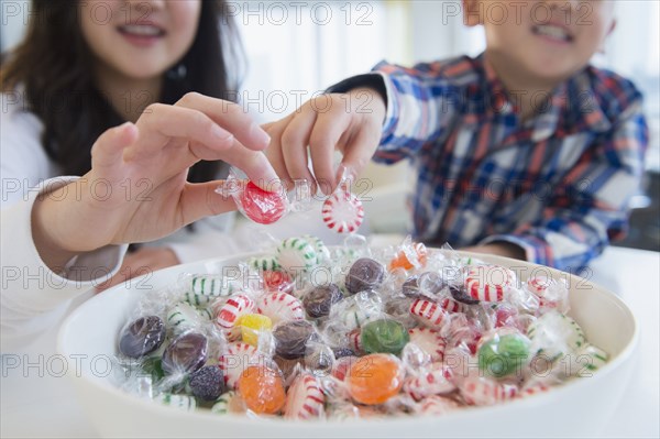 Asian brother and sister picking candy from bowl
