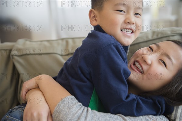 Asian brother and sister playing on sofa