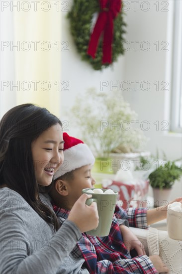 Asian brother and sister drinking hot cocoa at Christmas