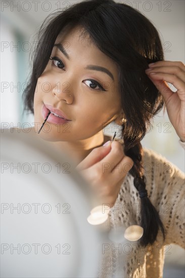 Pacific Islander woman braiding her hair