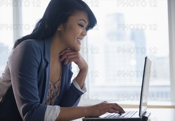 Pacific Islander businesswoman using laptop in office