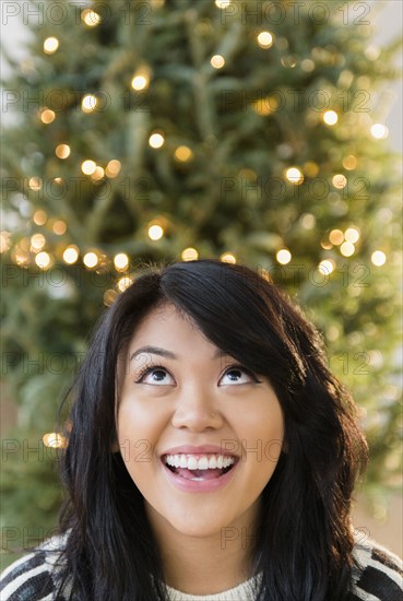 Pacific Islander woman looking up near Christmas tree