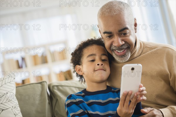 Mixed race grandfather and grandson using cell phone