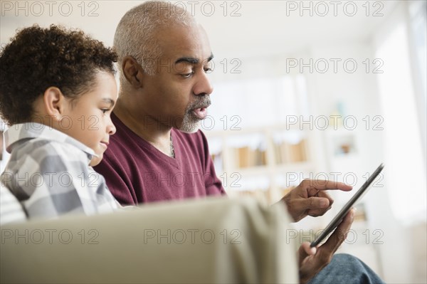 Mixed race grandfather and grandson using digital tablet