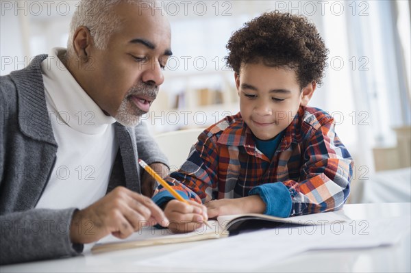 Mixed race grandfather helping grandson do homework