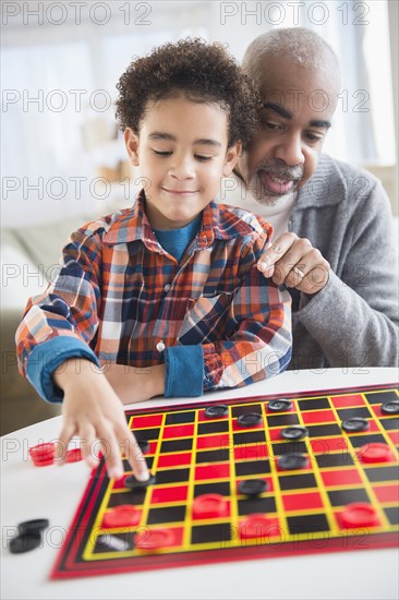 Mixed race grandfather and grandson playing checkers
