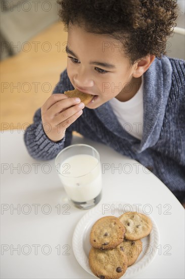 Mixed race boy eating cookies and milk