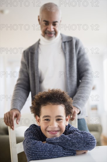 Mixed race grandfather and grandson sitting at table