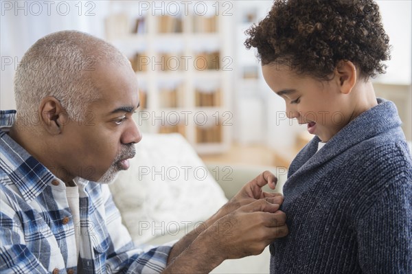 Mixed race grandfather buttoning sweater for grandson