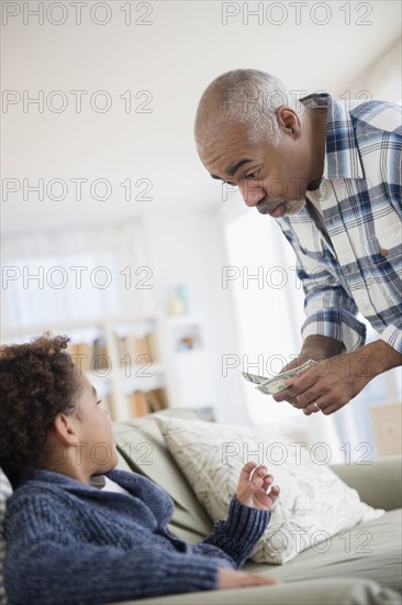 Mixed race grandfather giving money to grandson