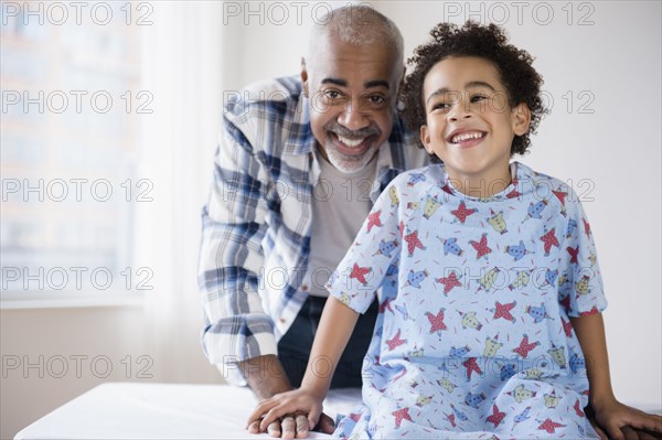 Mixed race grandfather smiling with grandson in hospital