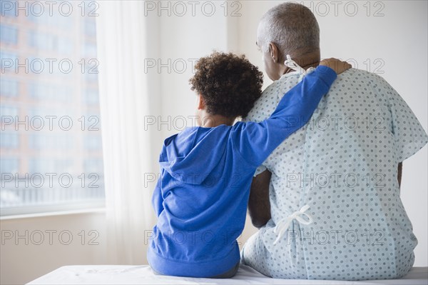 Mixed race grandfather sitting with grandson in hospital