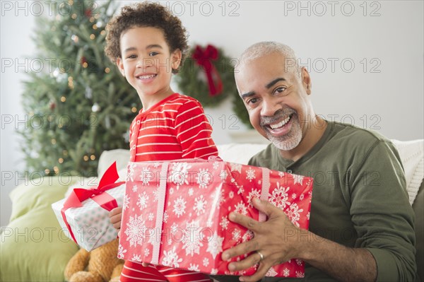 Mixed race grandfather and grandson opening Christmas gifts