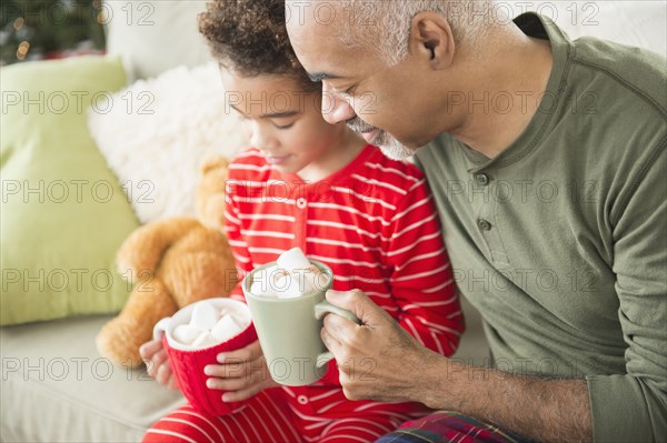 Mixed race grandfather and grandson drinking hot chocolate at Christmas