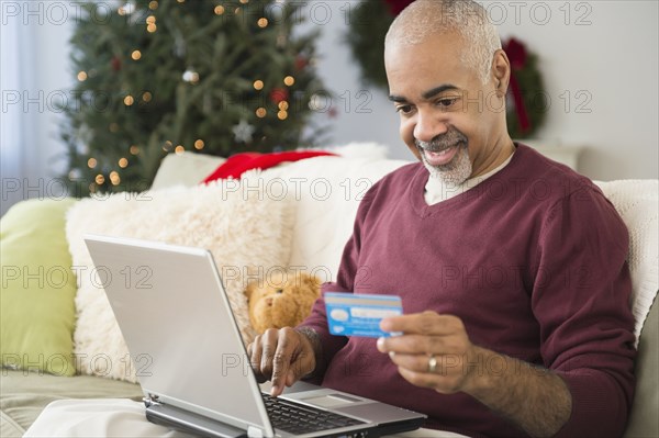 Mixed race man shopping online with laptop at Christmas